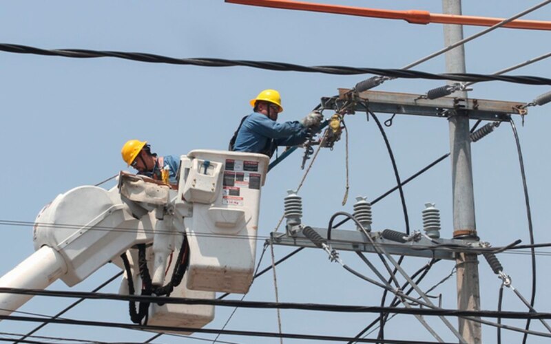 Dos trabajadores de la luz arreglando un cable
