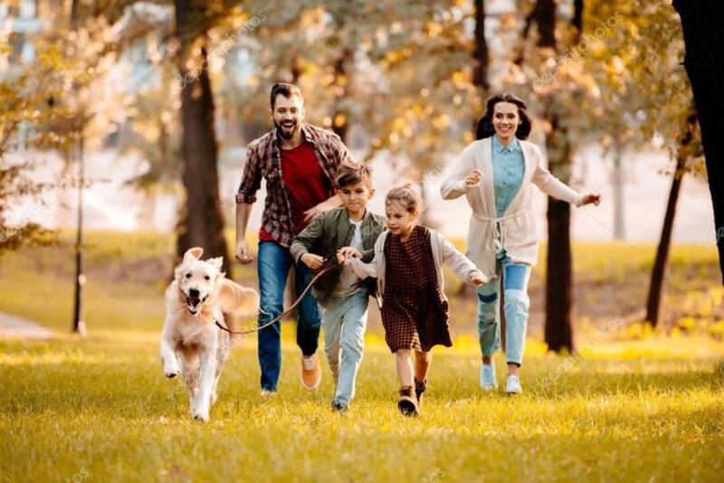Familia feliz corriendo en el parque con su perro