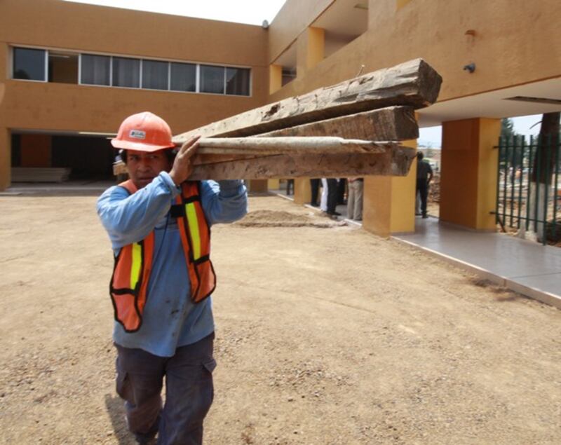 Un trabajador de la construcción lleva tablones de madera