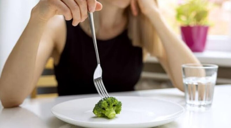 Mujer joven comiendo brócoli