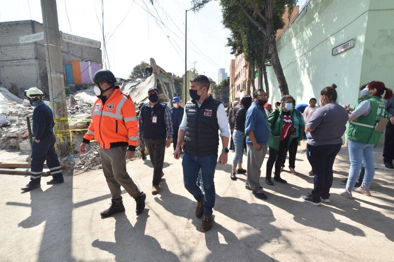 Rescatistas y civiles caminan entre los escombros de un edificio colapsado tras un terremoto.