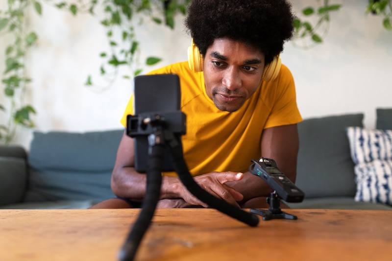 Un hombre negro joven está usando un teléfono inteligente para grabar un video