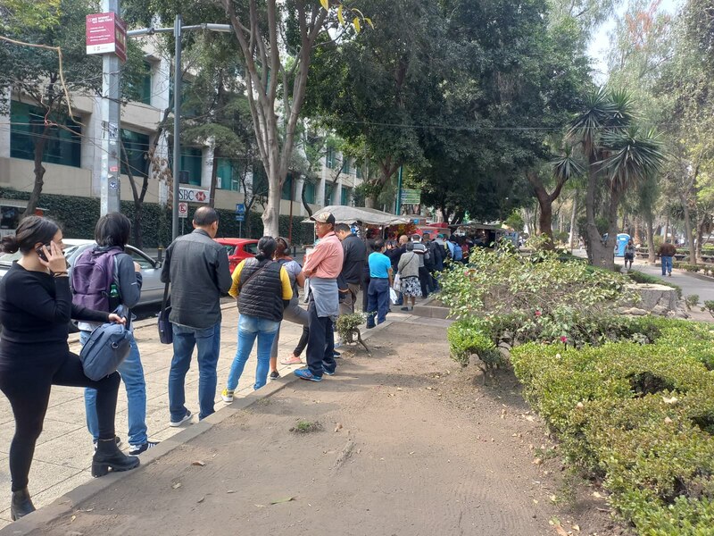 Larga fila de personas esperando para comprar comida en un puesto callejero en la Ciudad de México.