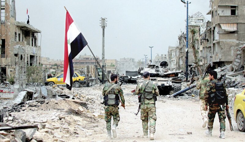 Soldados sirios caminan por una calle destruida en Aleppo