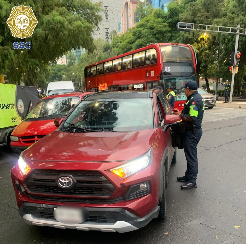 Posible título: Un policía detiene un coche rojo en una calle de la Ciudad de México