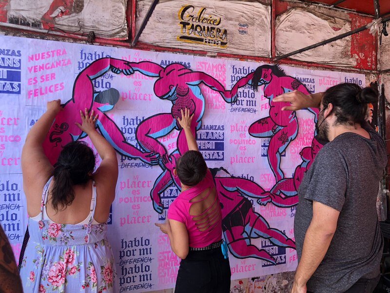 Title: Mujeres colocando carteles en una pared