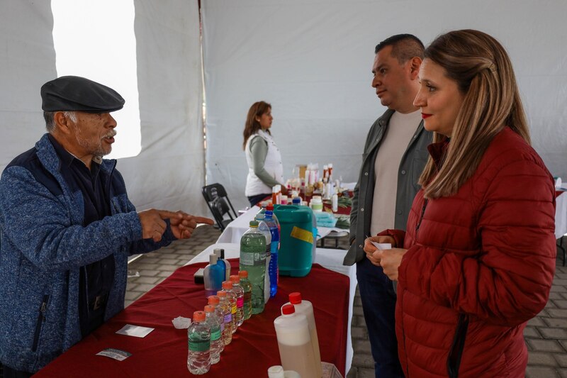 Un vendedor ambulante muestra sus productos a una pareja en un mercado.