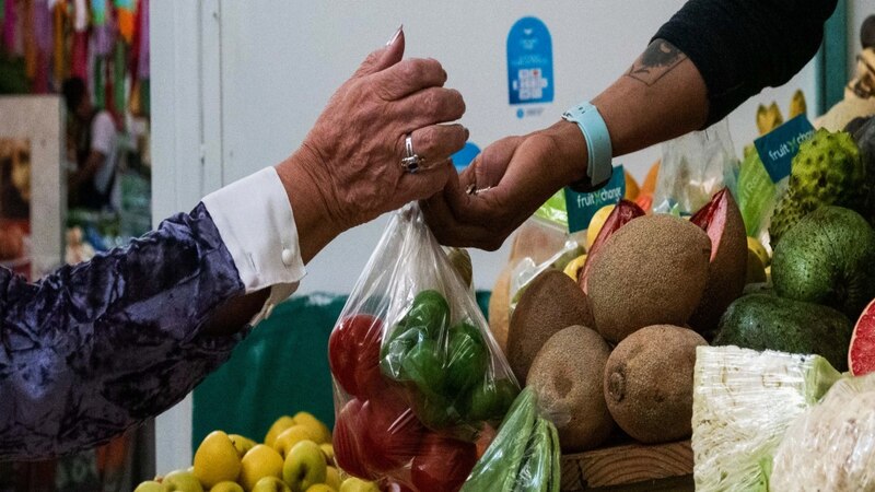 Mujer comprando frutas y verduras en un mercado local