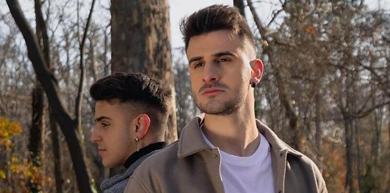Dos jóvenes cantantes urbanos sonríen a la cámara.