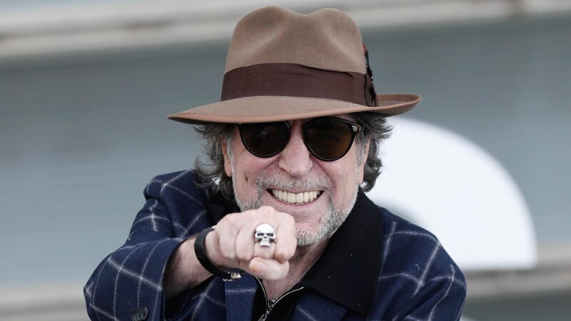 El cantante Raphael, con su característico sombrero y gafas de sol, sonríe y saluda a sus fans.