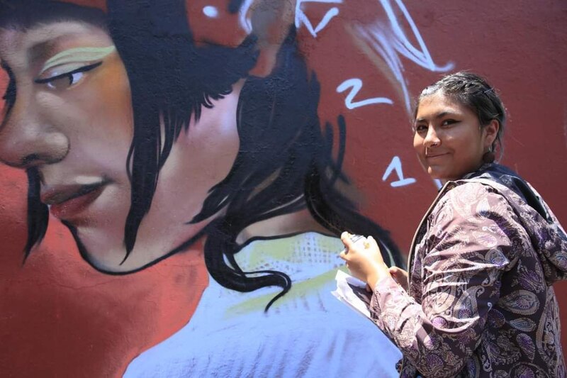 Artista urbana pinta un mural en la calle