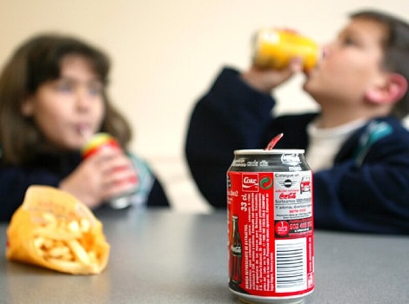 Niños comiendo comida rápida y bebiendo refrescos