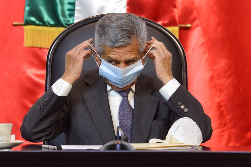El presidente López Obrador se pone una mascarilla durante una conferencia de prensa
