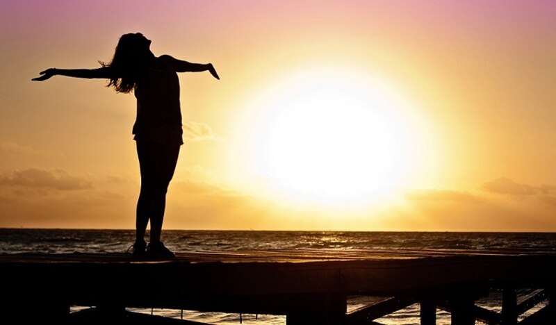 Mujer disfrutando de la puesta de sol en el mar