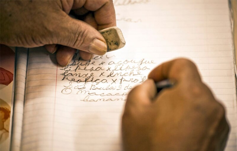 Una persona mayor escribe en un cuaderno.