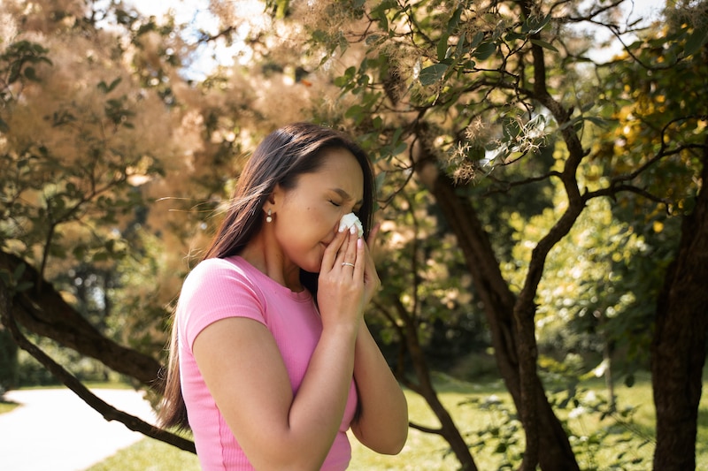 Mujer joven estornudando al aire libre