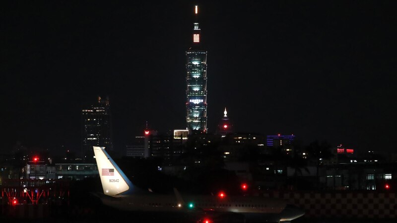 Un avión aterriza en el aeropuerto de Taipéi con el Taipei 101 iluminado de fondo