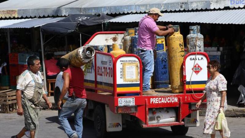 Un hombre carga un tanque de gas en un camión en un mercado en Venezuela
