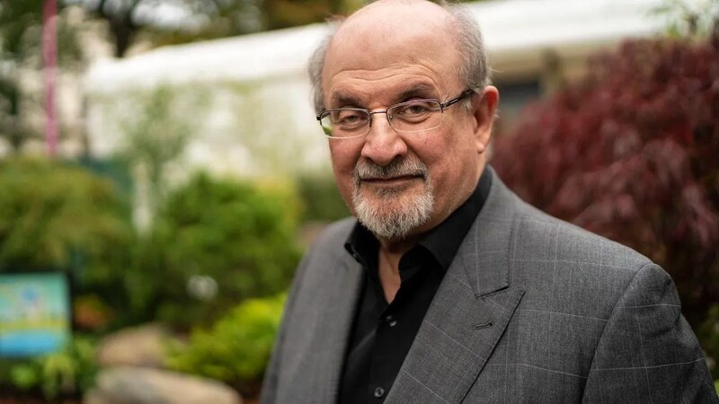 El autor Salman Rushdie sonríe a la cámara.