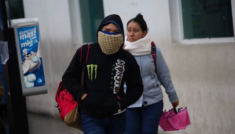 Jóvenes caminando por la calle con mascarillas