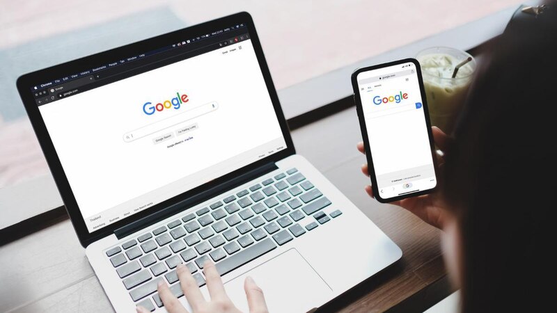 Mujer usando Google en su laptop y teléfono