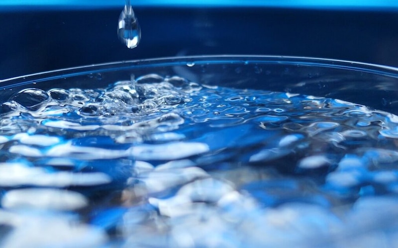 Primer plano de una gota de agua cayendo en un vaso de agua.