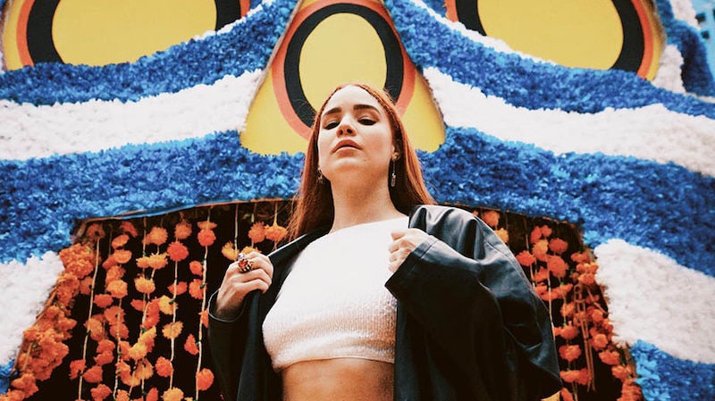 La cantante Rosalía posa para una foto con un colorido mural de fondo.