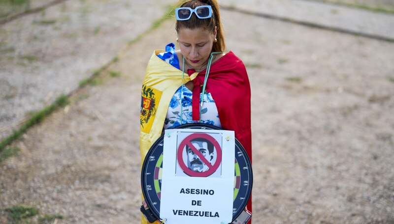 Mujer venezolana sostiene una pancarta con la cara de Nicolás Maduro y la palabra "asesino"