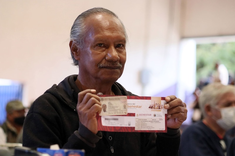 Un hombre de la tercera edad  es fotografiado al recibir su tarjeta bancaria para que pueda cobra su Pensión para el Bienestar.