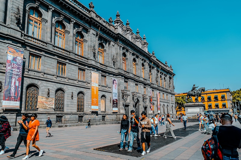 Grupo de personas recorriendo una exposición en un museo en México, con vitrinas y obras en exhibición.