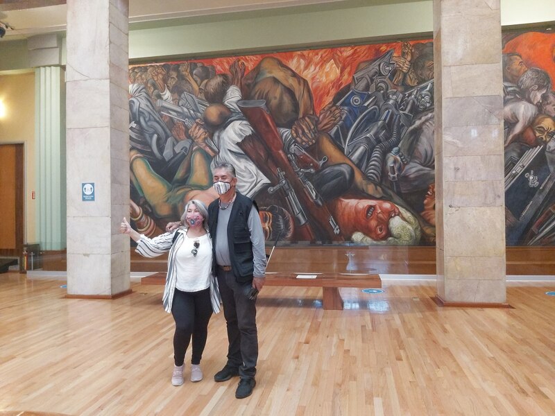 Pareja de pie frente a un mural histórico
