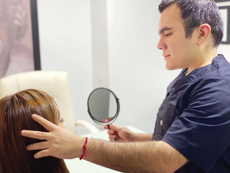 Doctor examinando el cuero cabelludo de una paciente