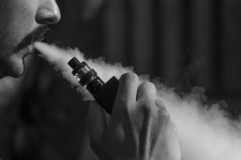 Joven vapeando, ilustrando el aumento de enfermedades pulmonares en usuarios de cigarros electrónicos, según especialistas de la UdeG