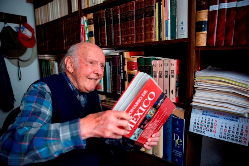 Un anciano lee un libro en una biblioteca