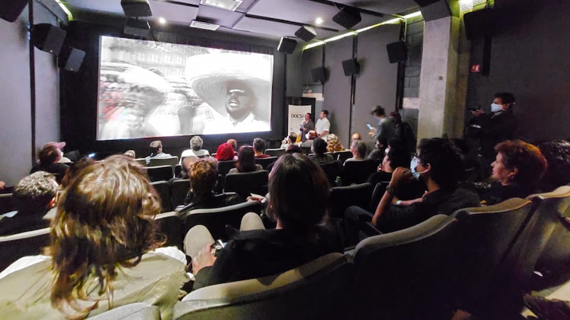 Función de cine en una sala oscura con butacas rojas