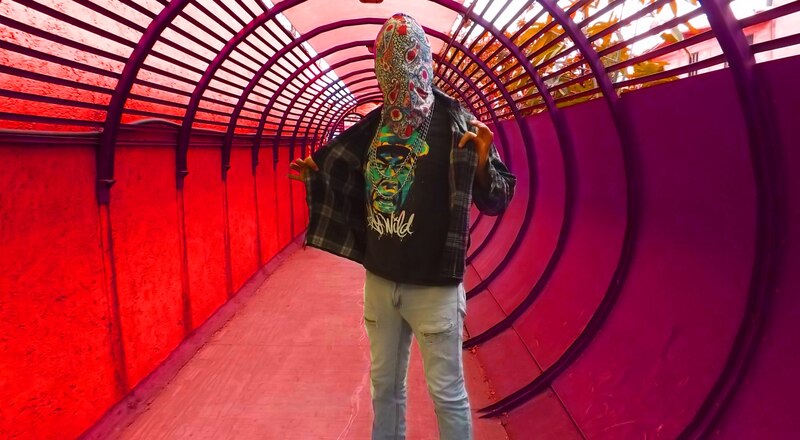 Un hombre con una máscara facial se encuentra en un túnel de color rosa.