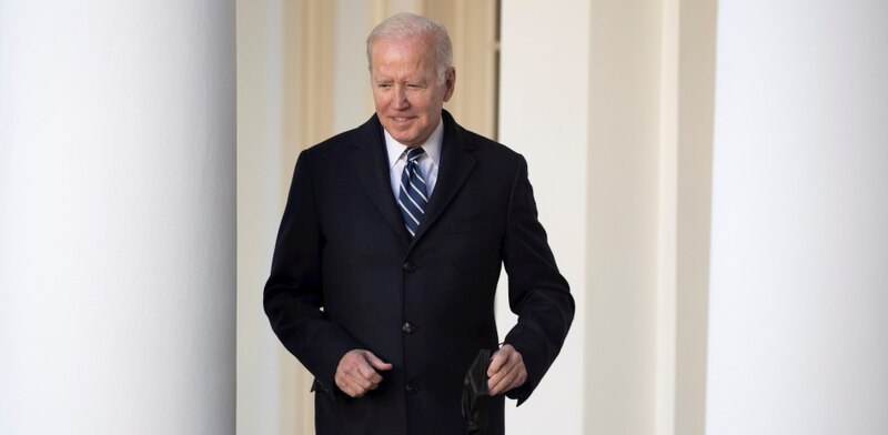 El presidente Biden sonríe mientras camina por la Casa Blanca