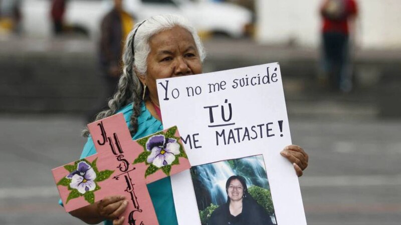 Mujer sostiene un cartel que dice "Yo no me suicidé, tú me mataste"