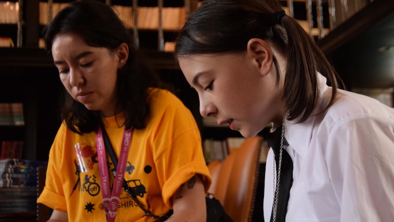 Dos mujeres jóvenes están leyendo en una biblioteca.