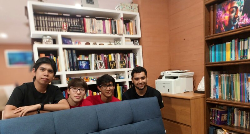 Cuatro estudiantes universitarios sonríen en una biblioteca