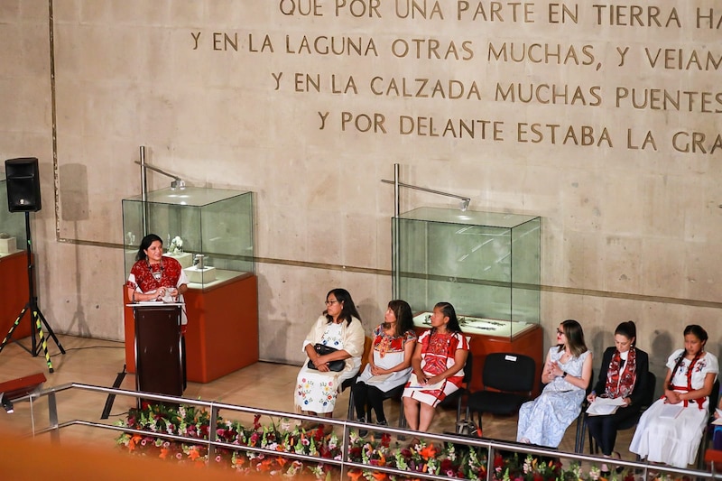 Discurso de una mujer en un podio frente a un público sentado