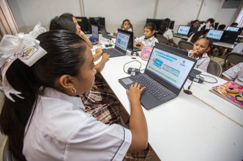 Niña usando una computadora portátil en una escuela.