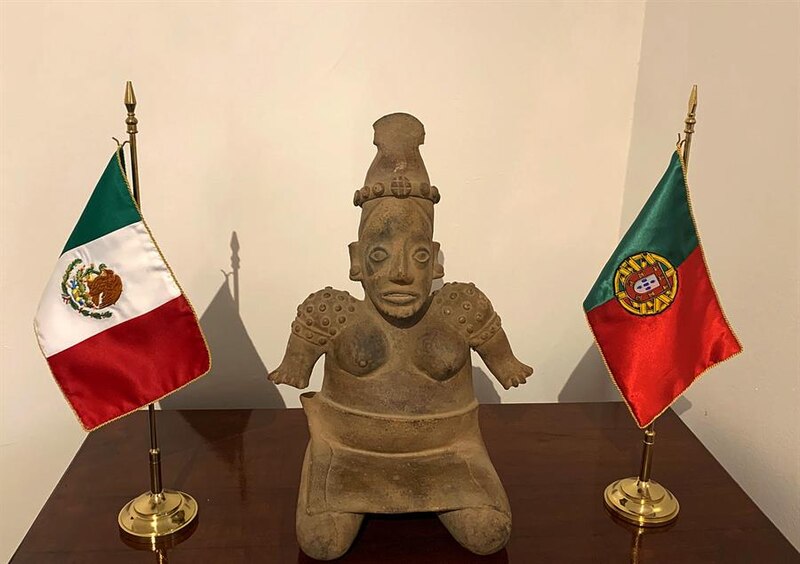 Estatua de mujer indígena con tocado y banderas de México y Portugal