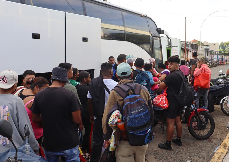 Migrantes esperan para abordar un autobús en la frontera entre Colombia y Venezuela