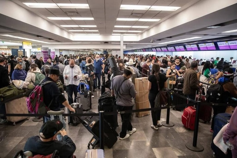 Pasajeros sentados y acostados en el suelo del Aeropuerto de Tijuana mientras esperan la reanudación de sus vuelos tras las afectaciones por la neblina