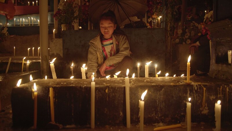 Una niña enciende velas en un altar durante el Día de Muertos