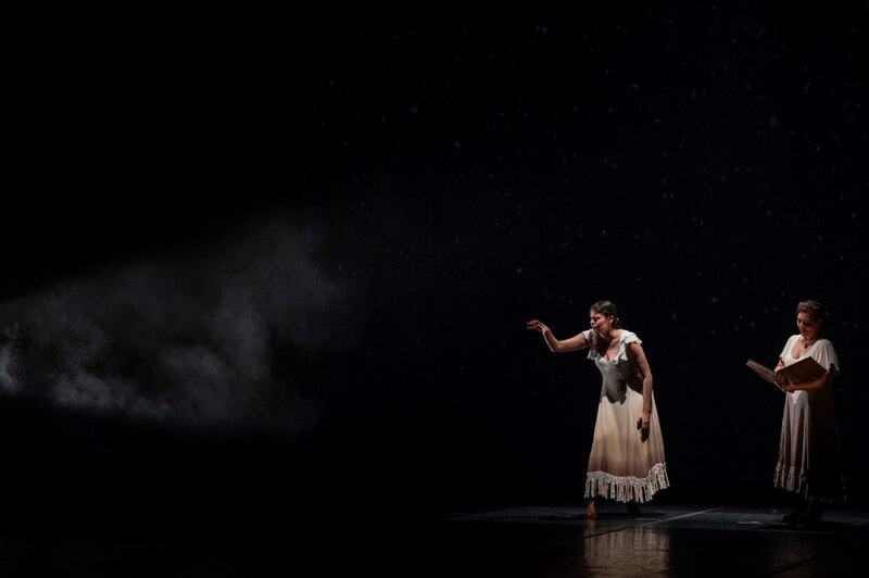 Dos mujeres bailando flamenco en un escenario oscuro