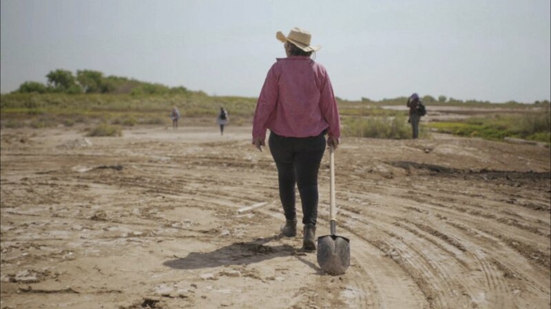 Mujer caminando con una pala en un campo