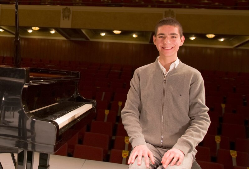 Joven pianista sentado junto a un piano de cola