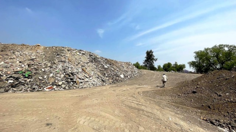 Un hombre camina por un vertedero de basura